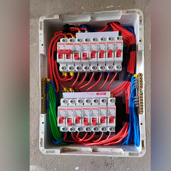 Quadro de distribuição montado com disjuntores alinhados e cabos identificados por cor