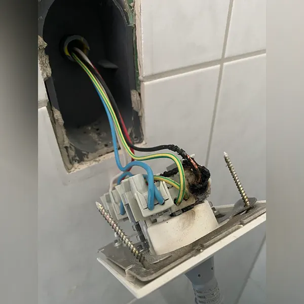 Tomada solta na parede, com fiação exposta e mau contato